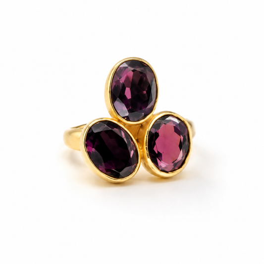 Gold-plated ring with three oval amethyst stones in deep purple tones.