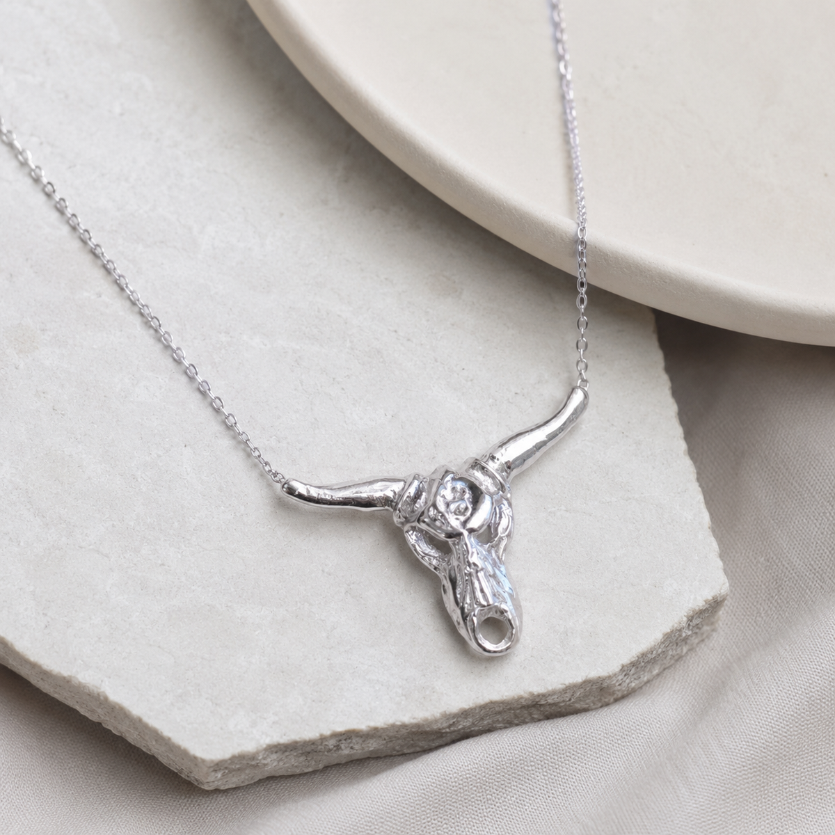 Angled view of a silver-tone longhorn pendant necklace.