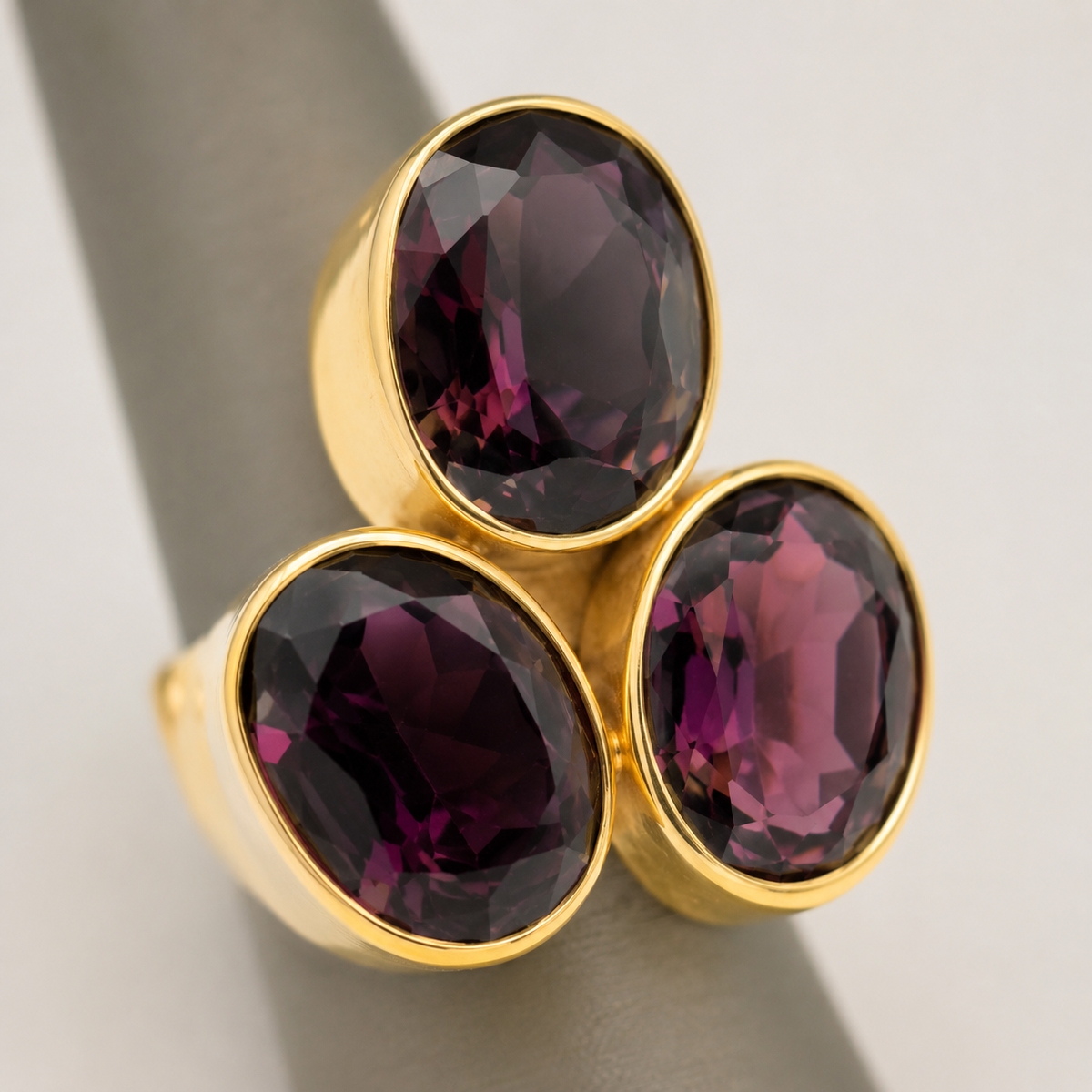 Close view of a gold ring with three faceted amethyst stones.