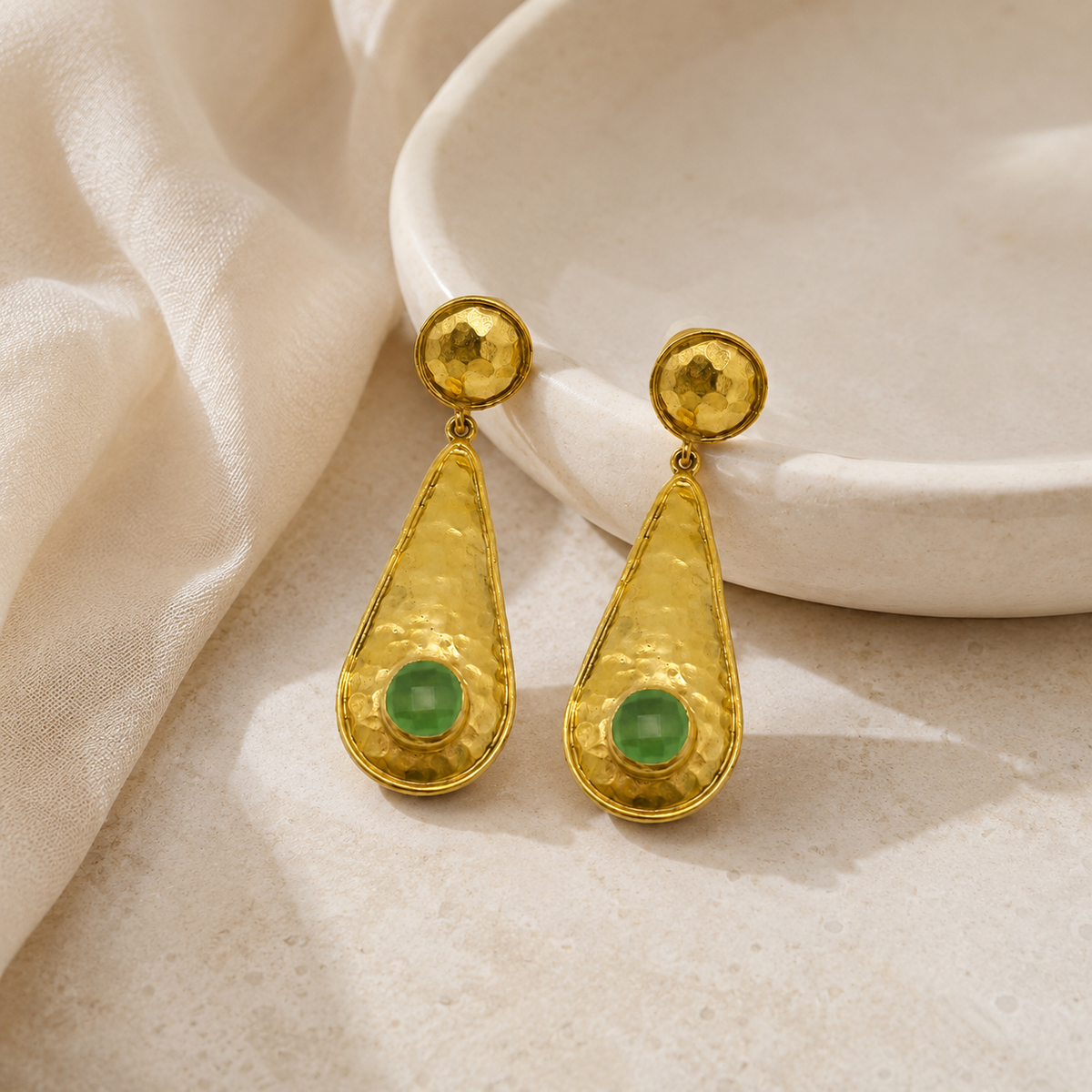Gold-tone teardrop earrings with a textured finish and green accent.