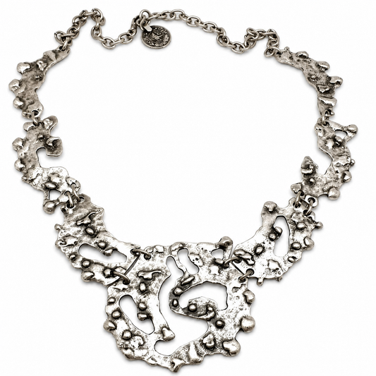 Organic silver-tone statement necklace with a sculptural pendant shape and textured finish.