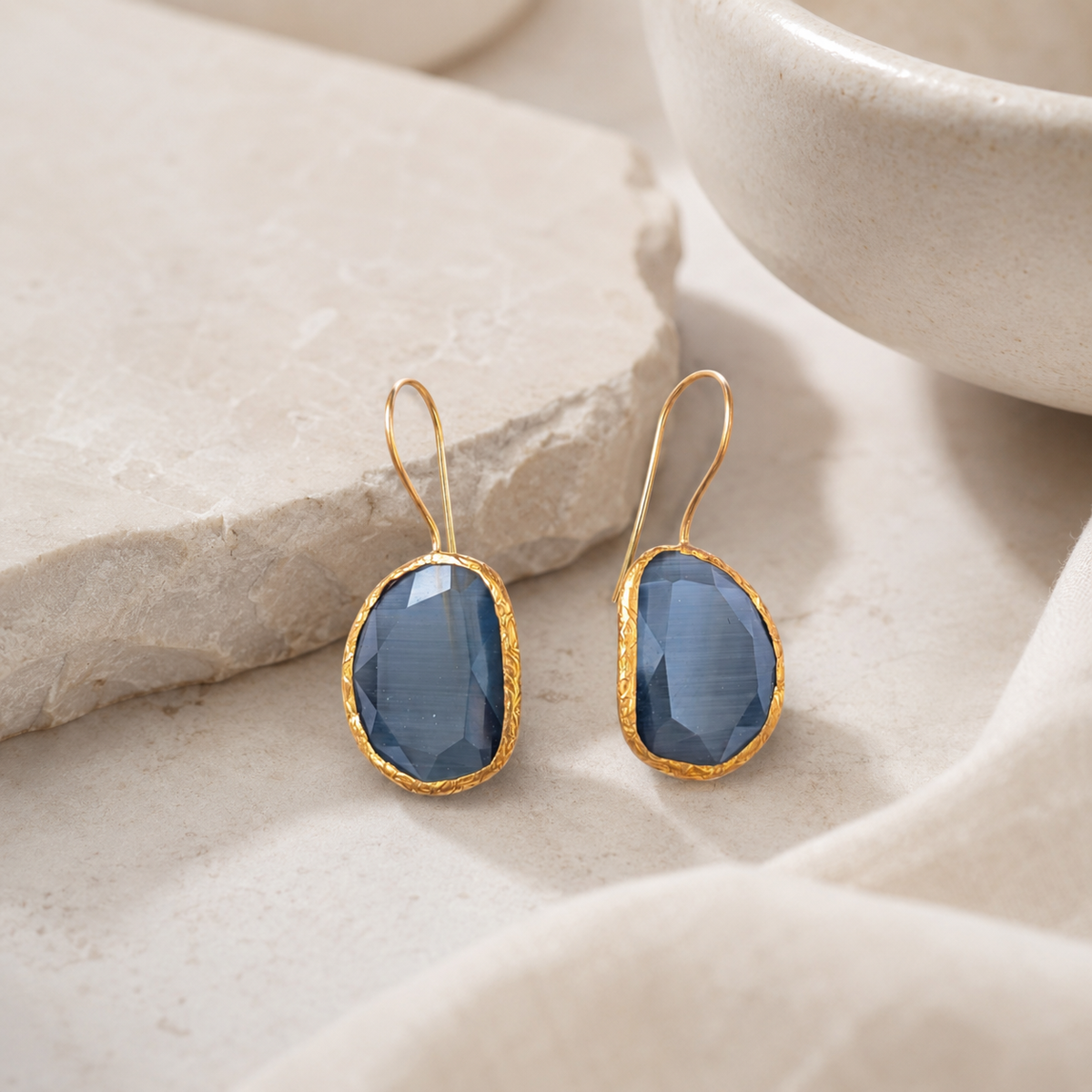 Gray teardrop drop earrings with a polished gold-plated look.