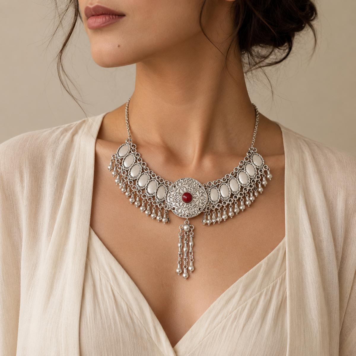 Front view of a silver-tone fringe necklace with a red center stone.