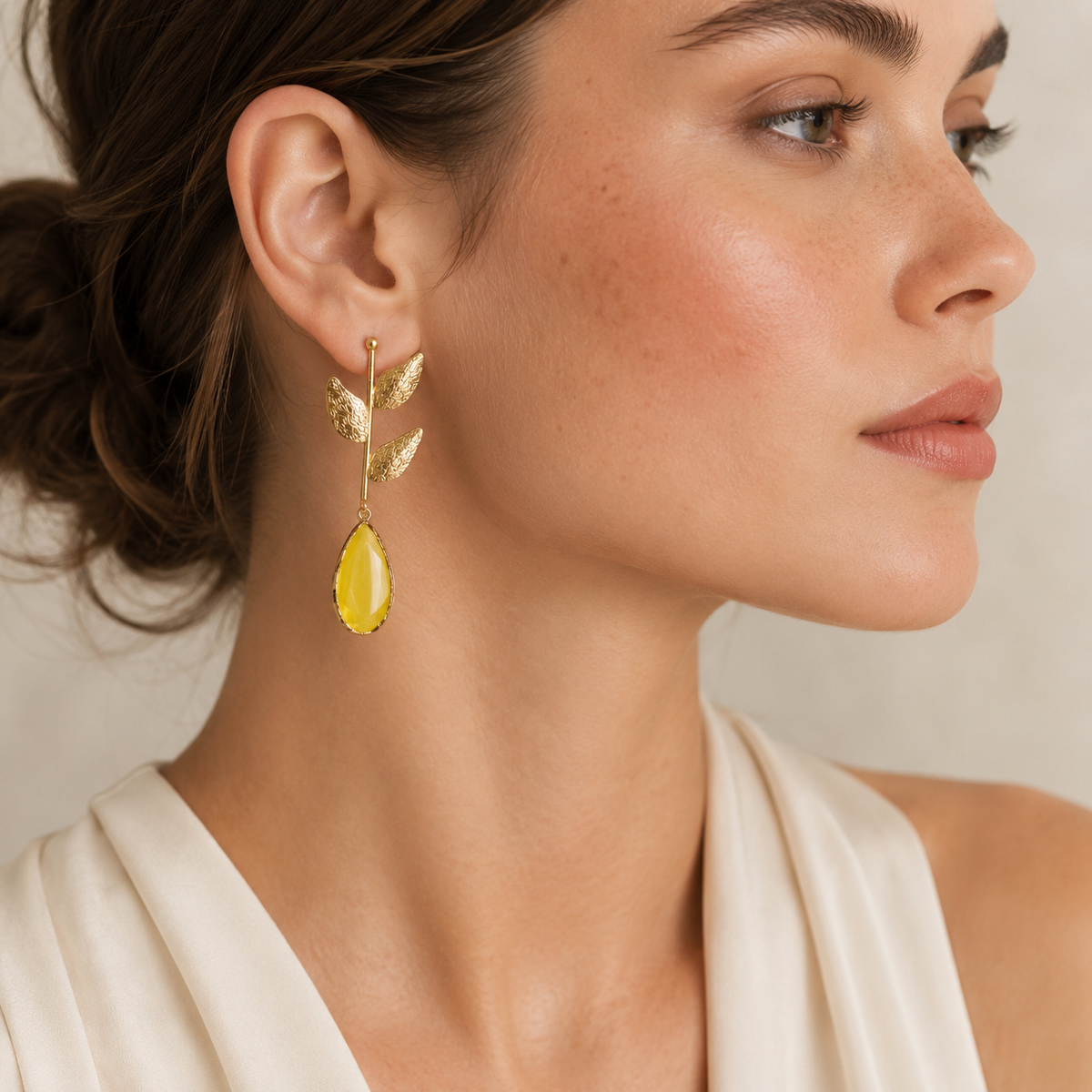 Gold plated leaf drop earrings with mustard yellow teardrop stones shown front view.