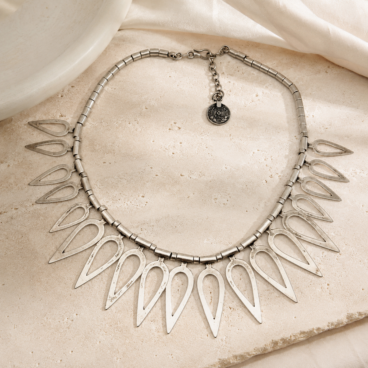 Silver-tone teardrop necklace with a modern collar shape and open pendant links.