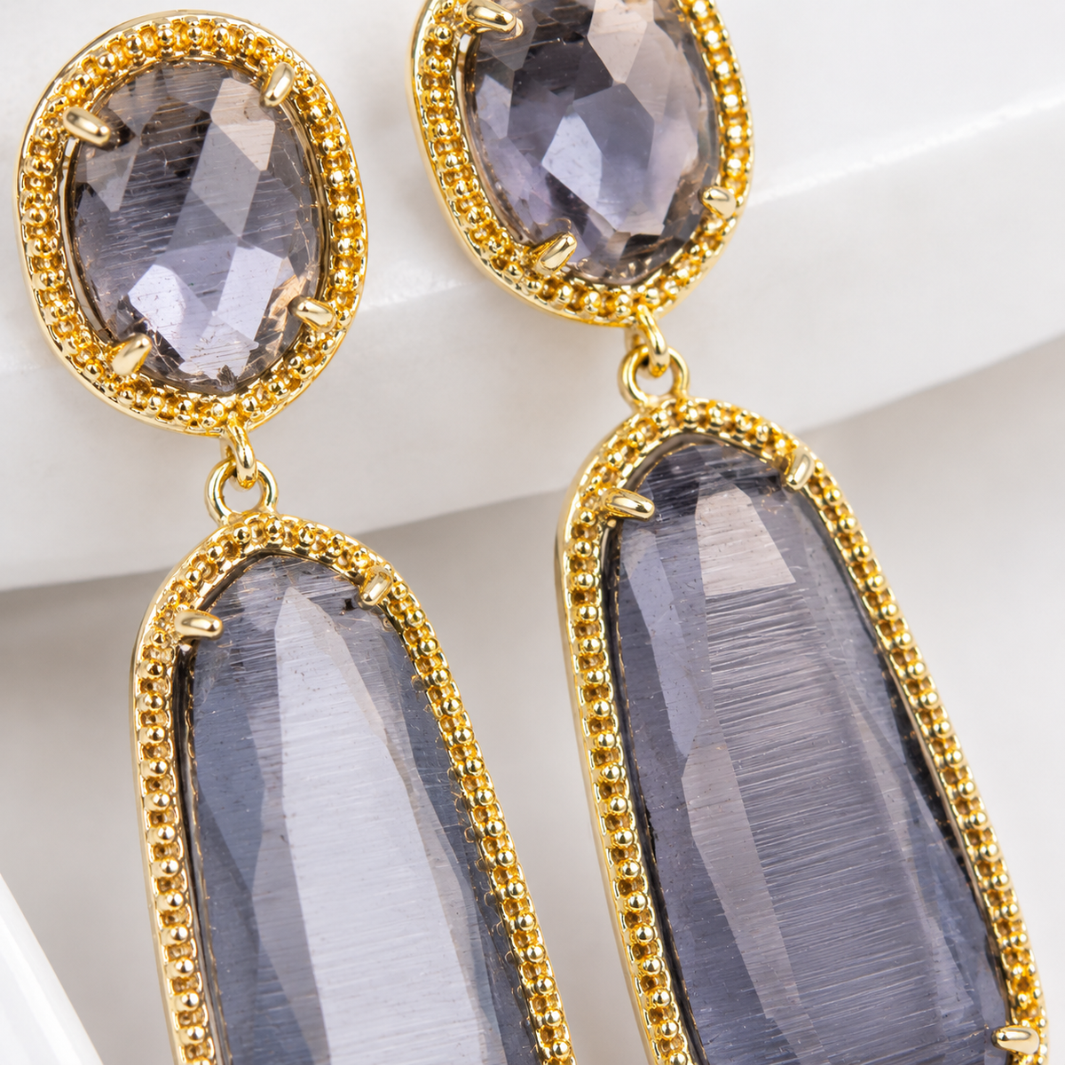 Close view of the faceted smoky gray stones and gold-plated setting.