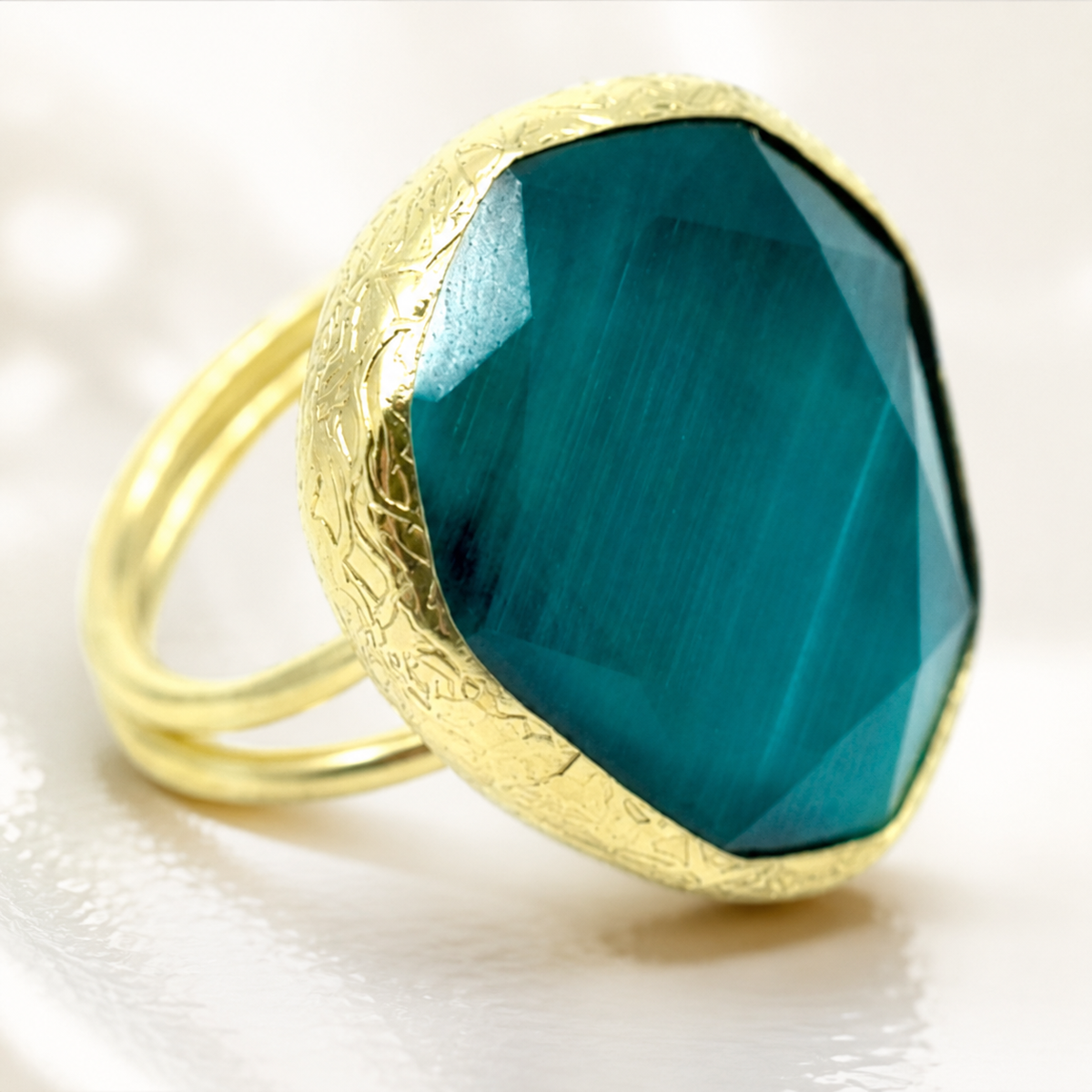 Close view of the faceted green stone and textured gold-tone setting.