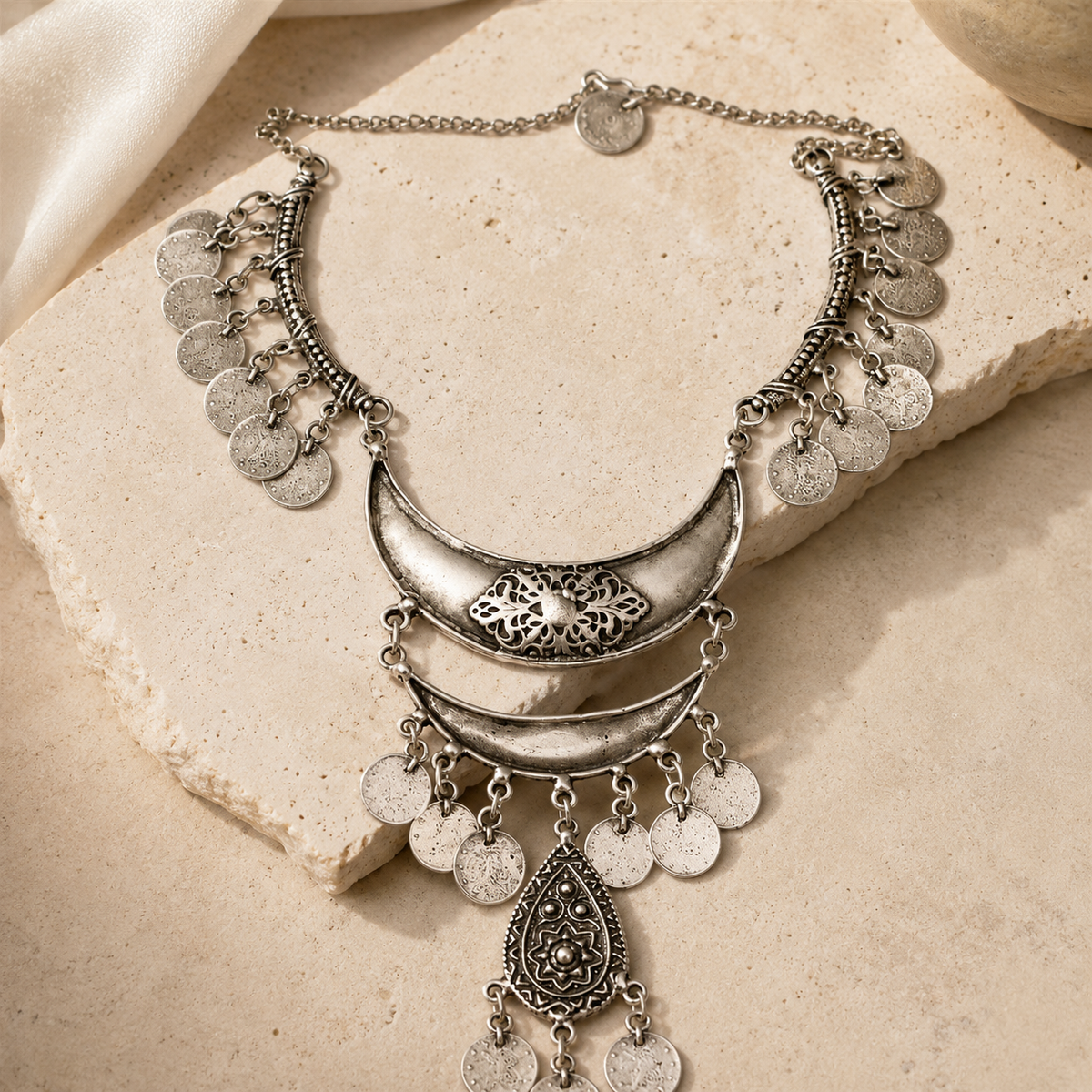 Silver-tone statement necklace with a layered bib shape and dangling coins.