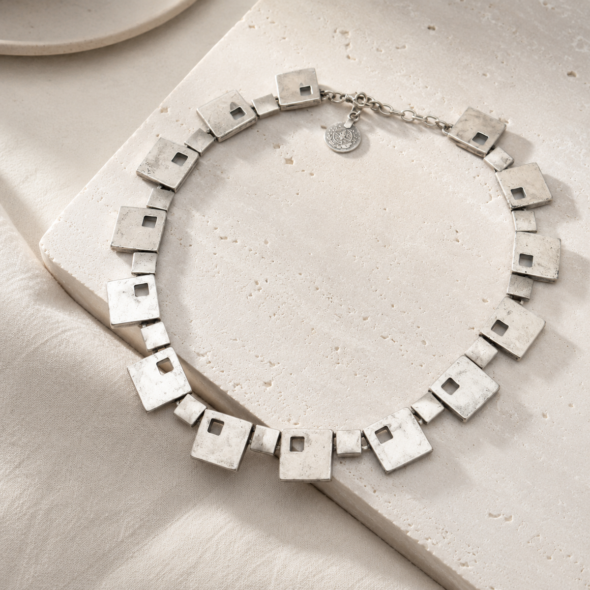 Angle view of a silver-tone necklace with square geometric links.
