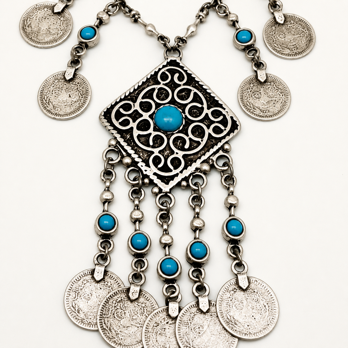 Close view of the silver medallion and turquoise details on the necklace.