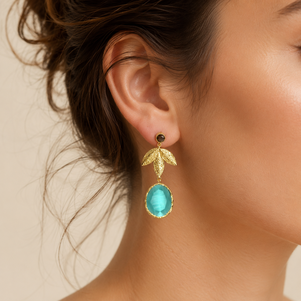 Pair of gold-tone leaf drop earrings with turquoise oval pendants.