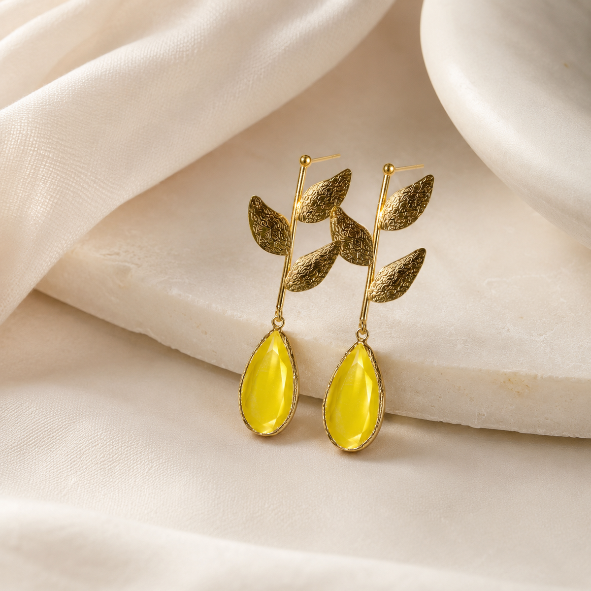 Gold plated drop earrings with a leaf motif and bright mustard yellow teardrop shape.