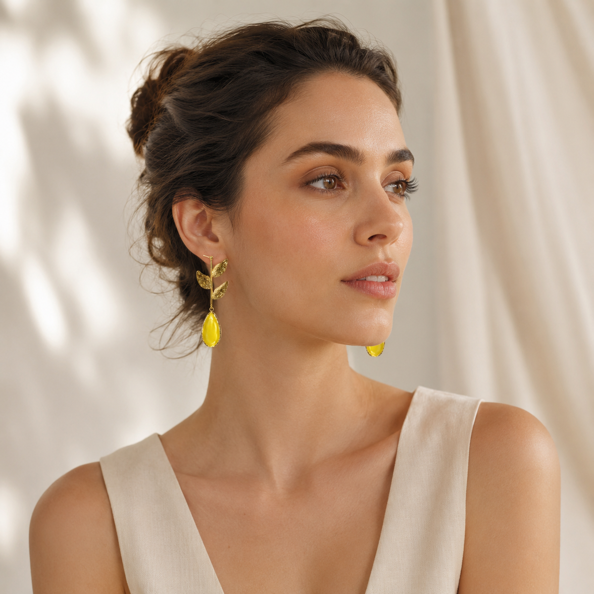 Gold plated leaf earrings with mustard yellow drops in a clean studio view.