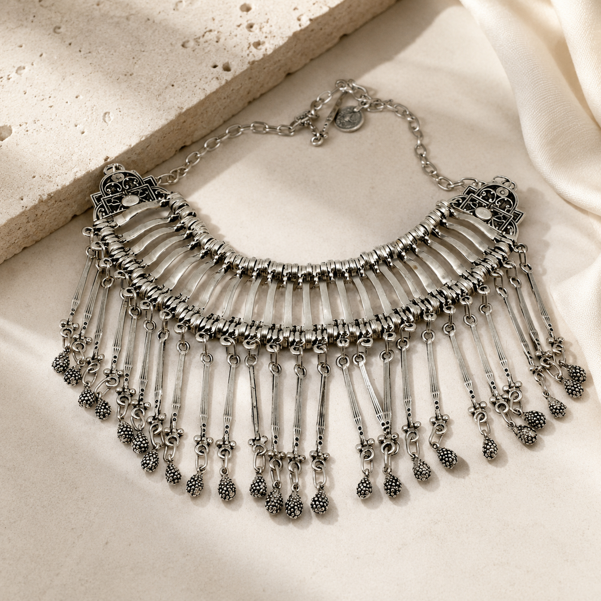 Silver-tone statement necklace with a wide bib silhouette and dangling fringe.