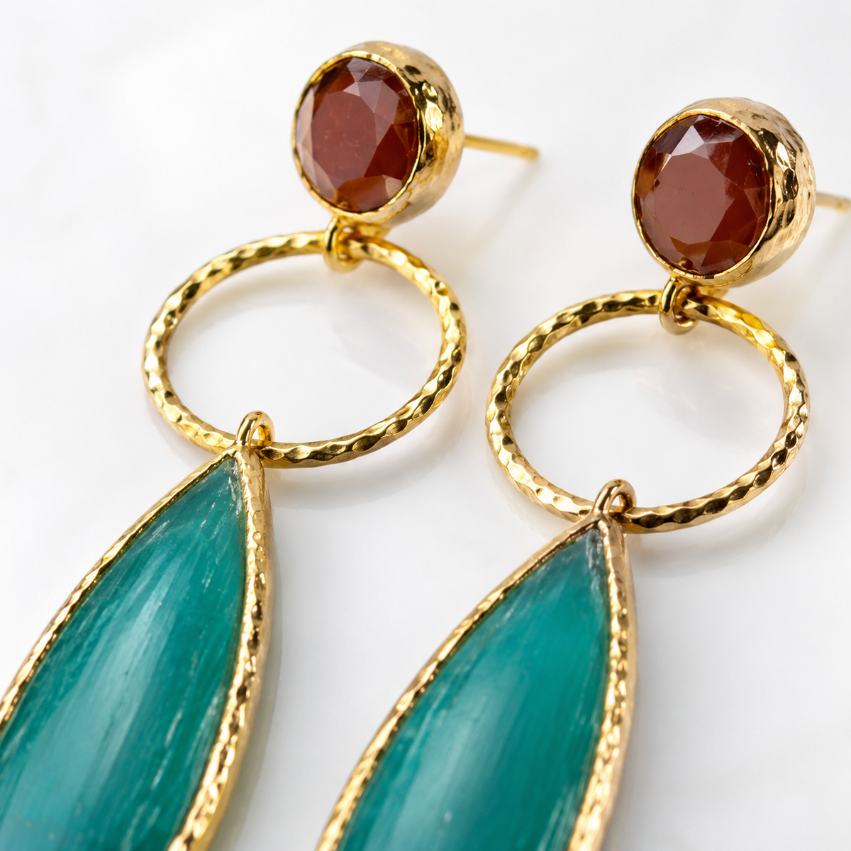 Gold-plated drop earrings with pine green leaf-shaped pendants and a small red stone top.