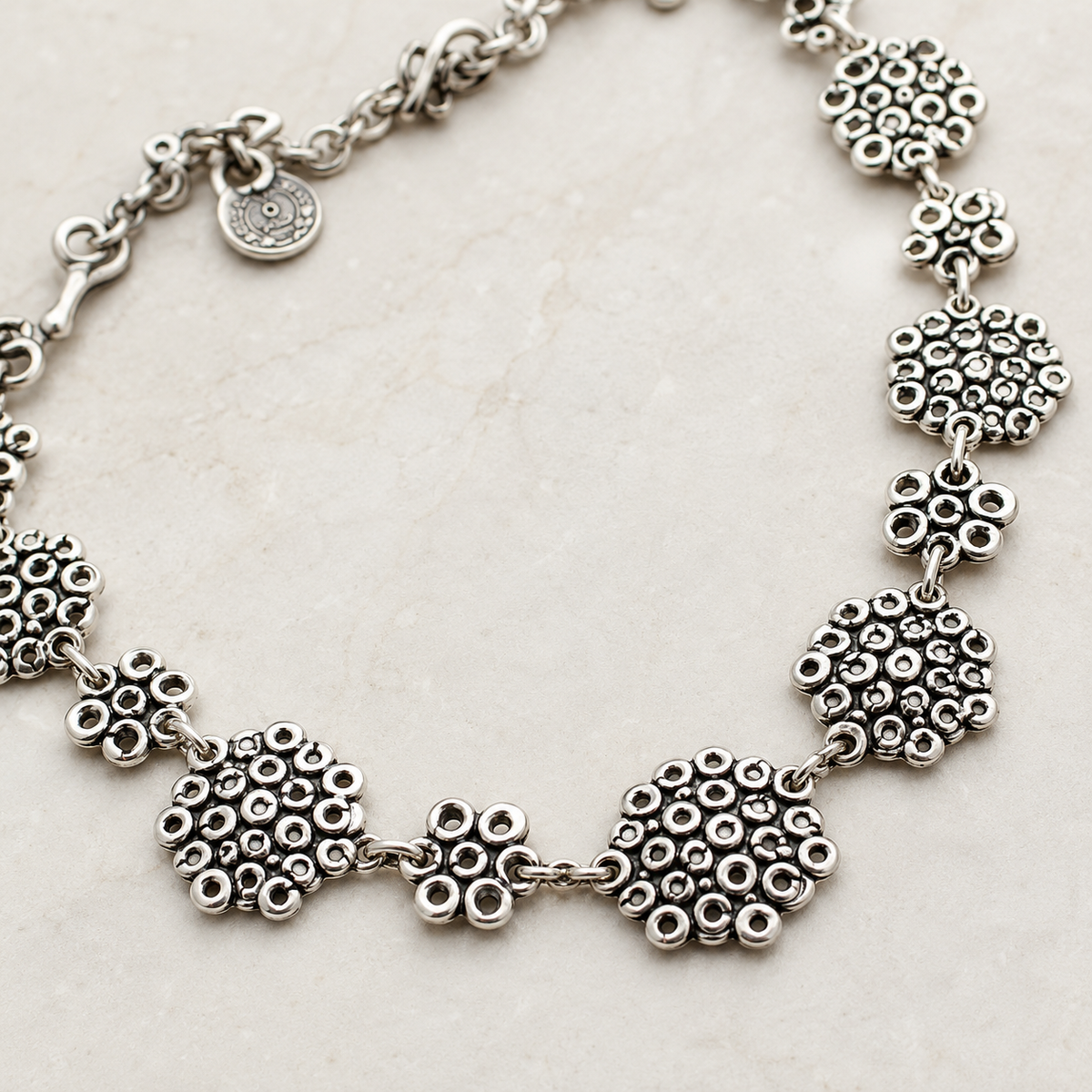 Close view of the necklace’s linked heart-inspired details and textured silver-tone finish.