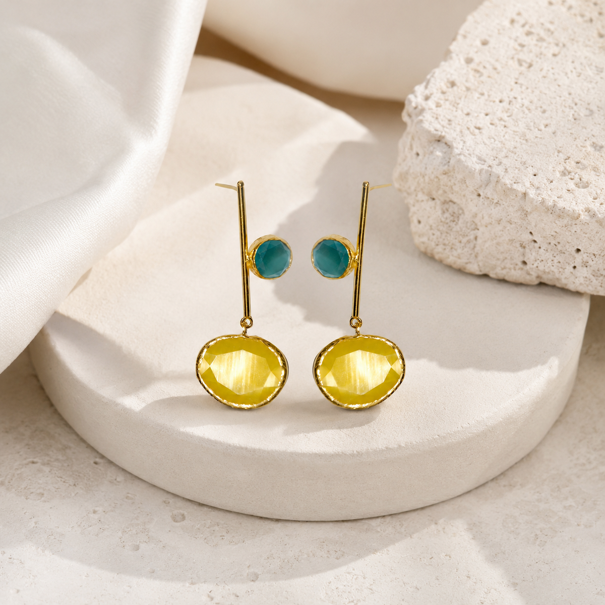 Modern gold-tone drop earrings with mustard yellow stones on a white background.