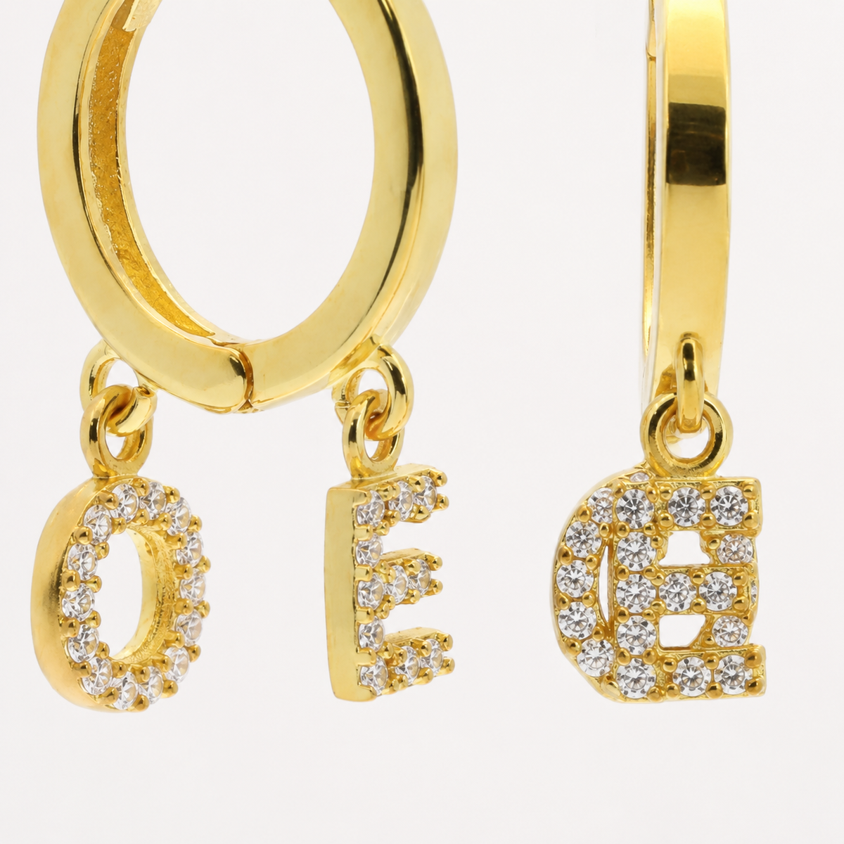 Close view of CZ initial charms hanging from a polished hoop.