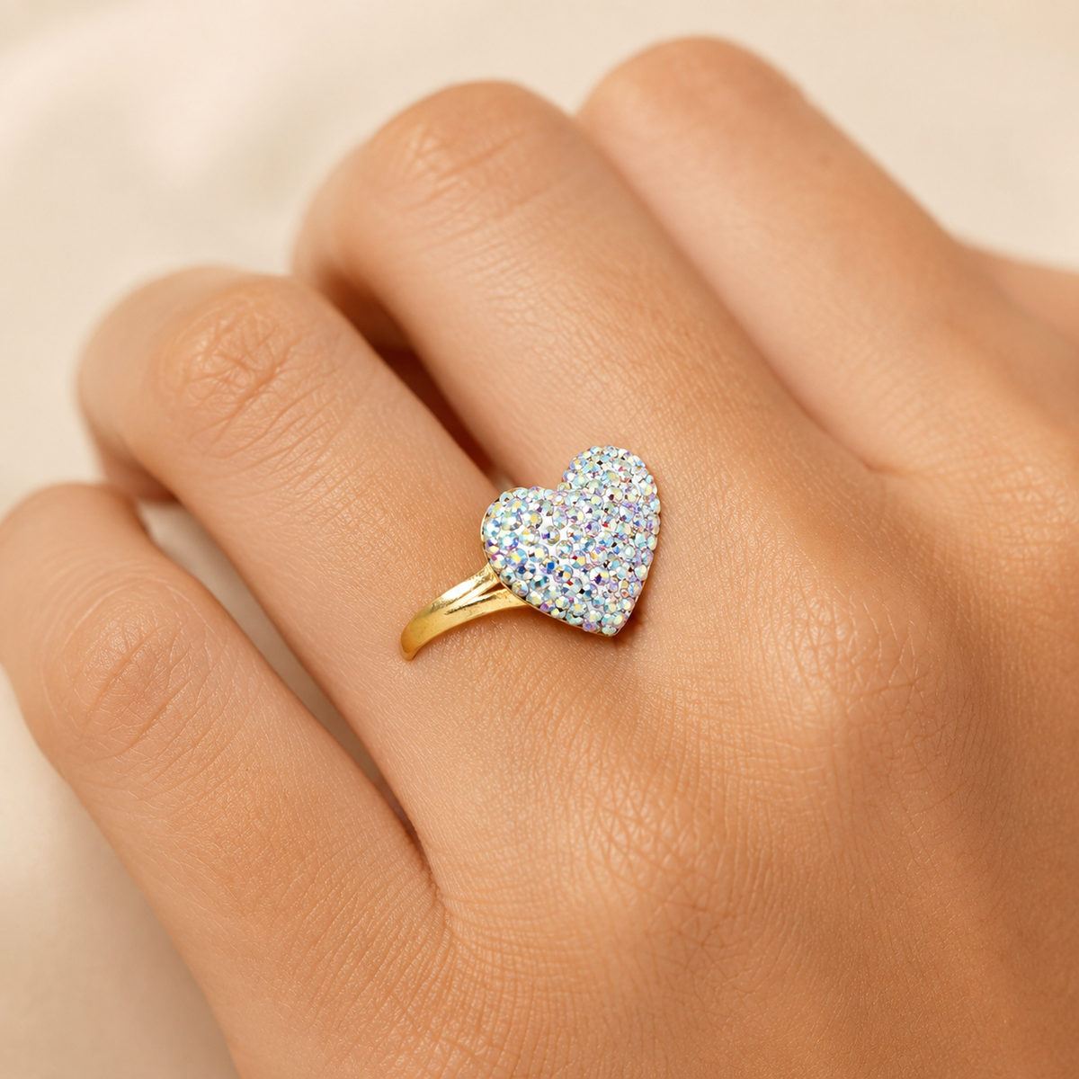 A gold-plated heart ring with a crystal-covered top shown from the side.