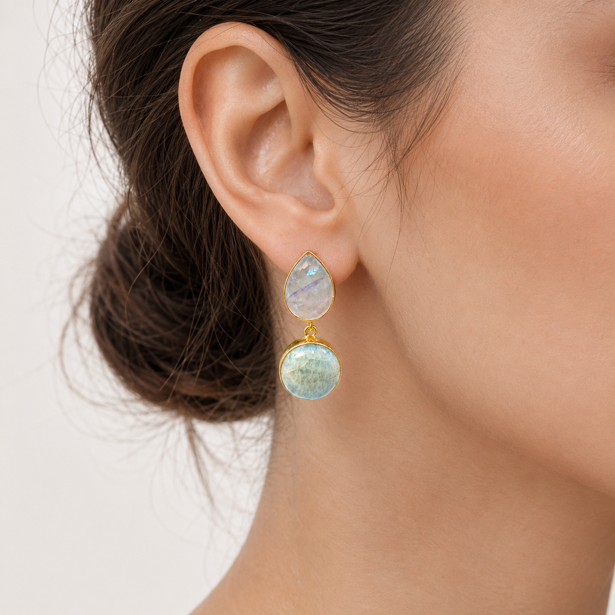 Gold-plated drop earrings with soft blue-green stones on a white background.