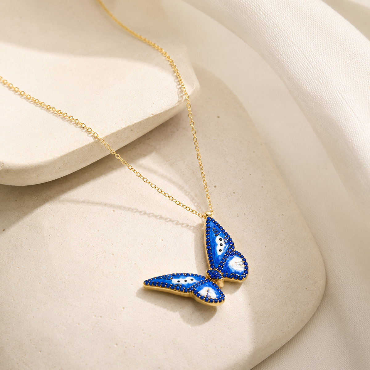 Angled view of a gold-tone necklace with a blue butterfly pendant.