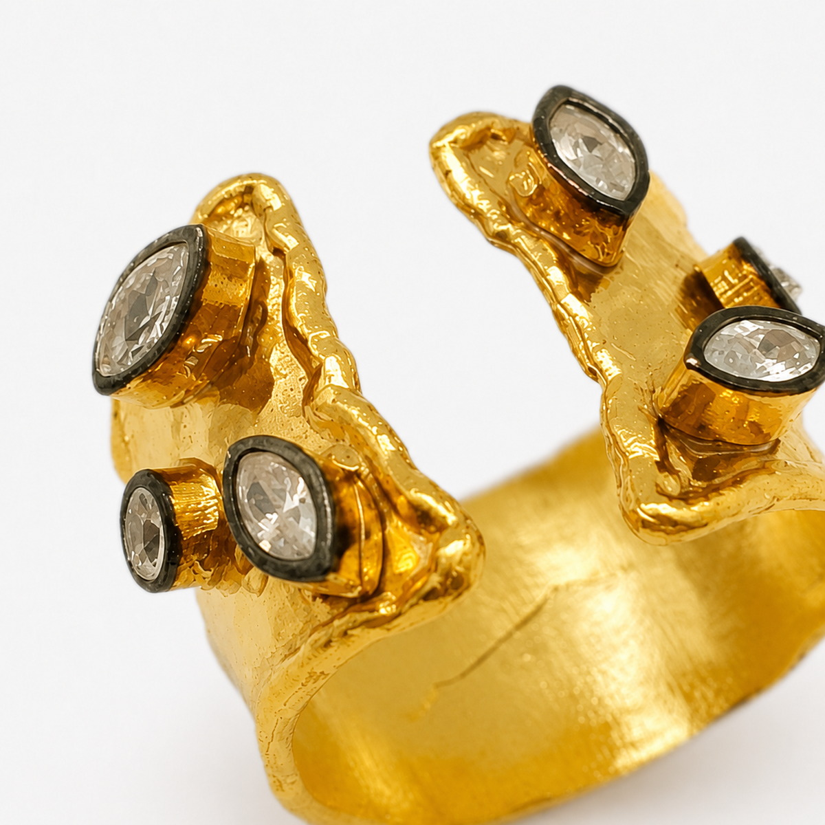 Detail view of a gold-plated open cuff ring with clear quartz stones.