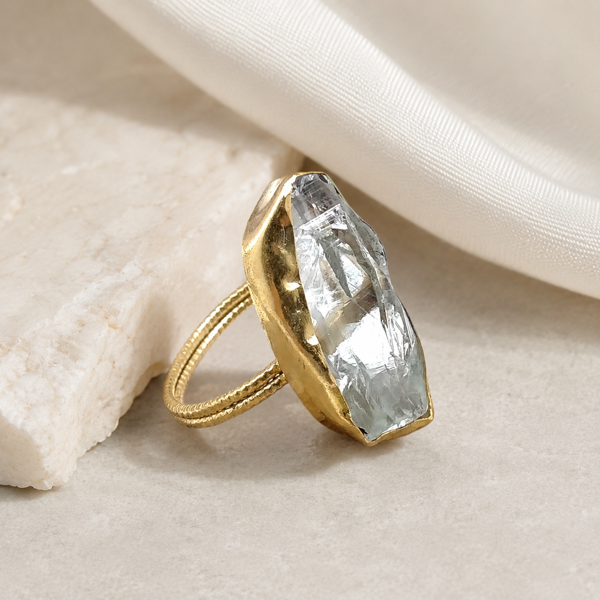 Gold-plated statement ring with a raw crystal quartz center on a white background.