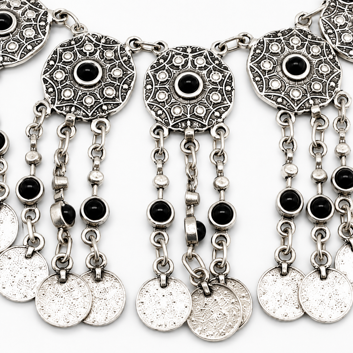 Close-up of the necklace's ornate silver-tone discs and black stone centers.