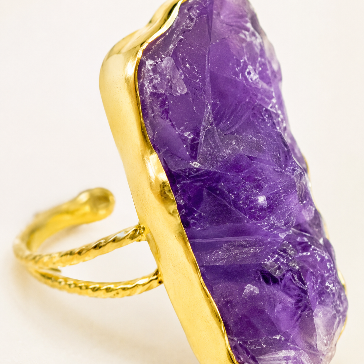 Close view of the raw purple amethyst stone and gold-plated frame.
