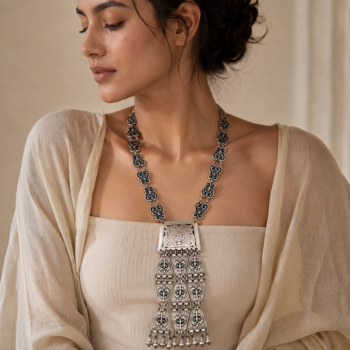 Front view of a silver-tone necklace with a geometric tassel pendant.