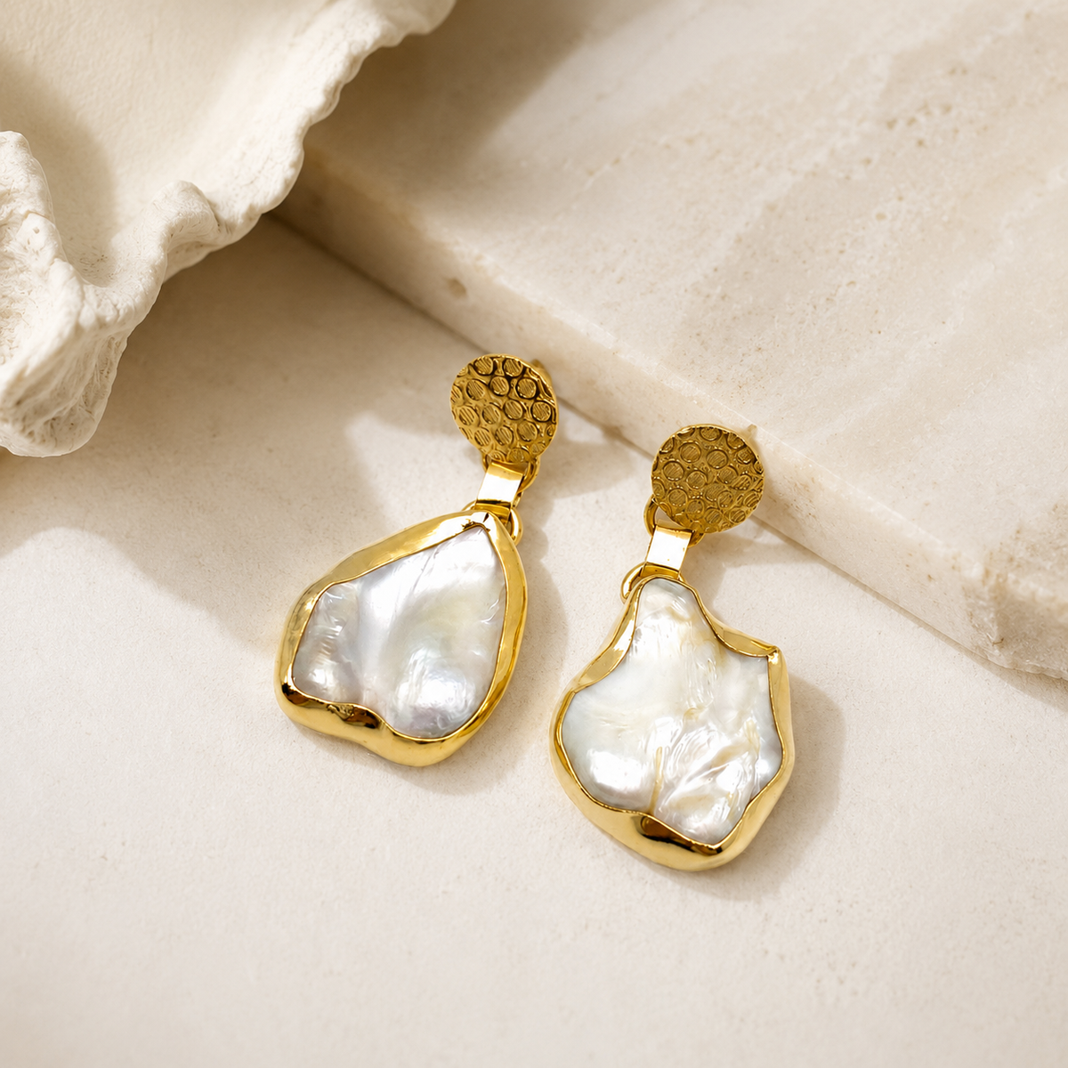 Gold earrings with mother of pearl drops shown on a clean white background.