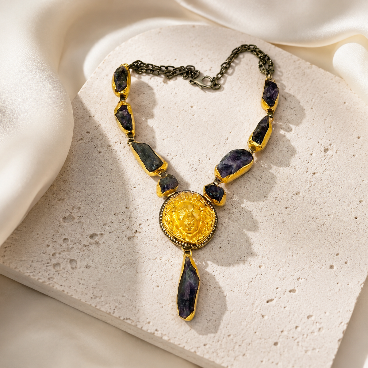Purple raw stone statement necklace styled with a gold-tone sunburst pendant.