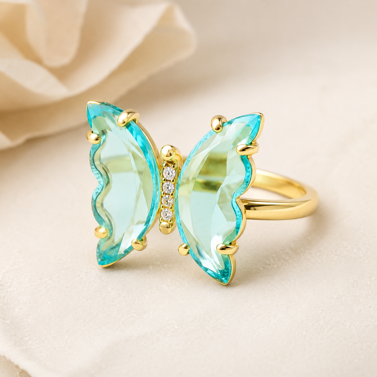 Angle view of a butterfly ring with sky blue topaz wings and gold-plated setting.