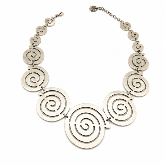Spiral circle statement necklace in a soft gold-tone finish on a white background.