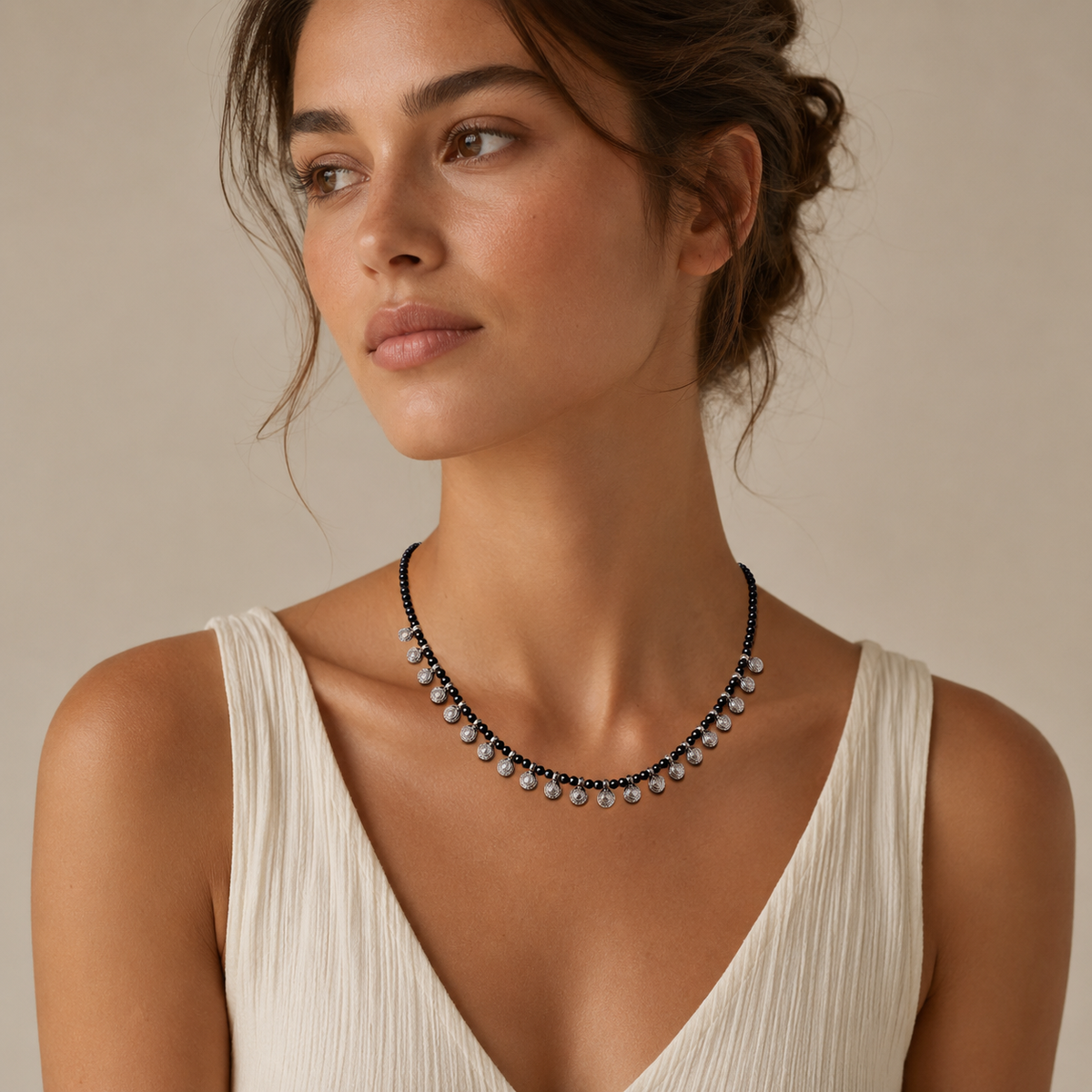 Black bead necklace with silver-tone round charms in a clean product image.