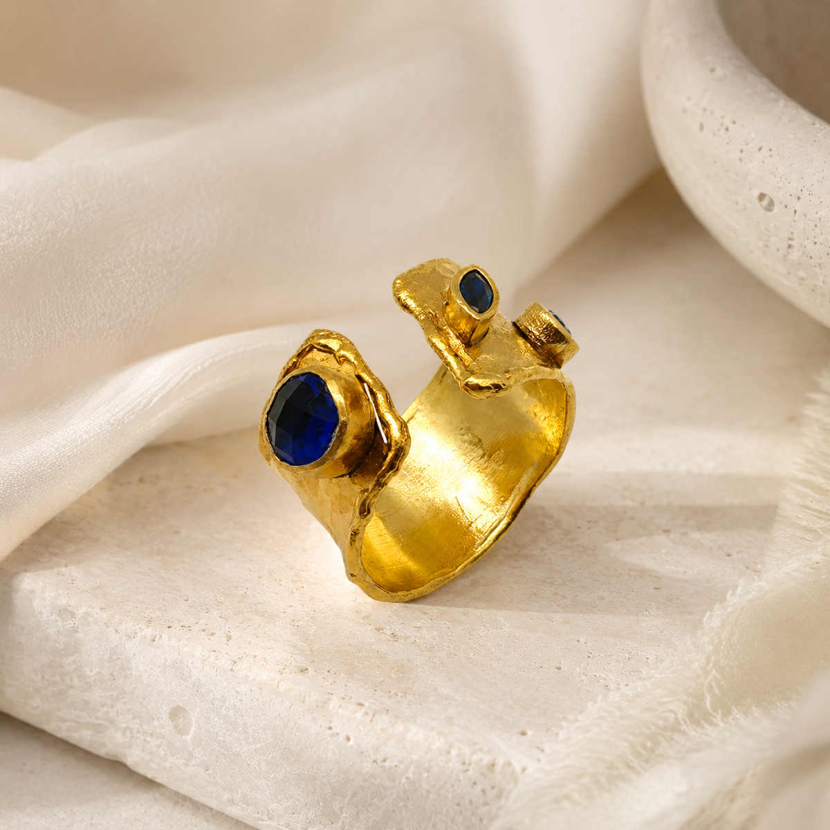 Gold open cuff ring with a bold sapphire blue accent.