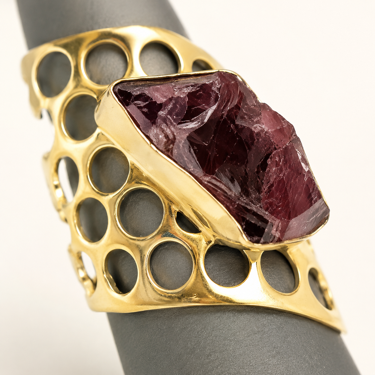 Close view of the raw garnet stone and openwork gold-plated band.