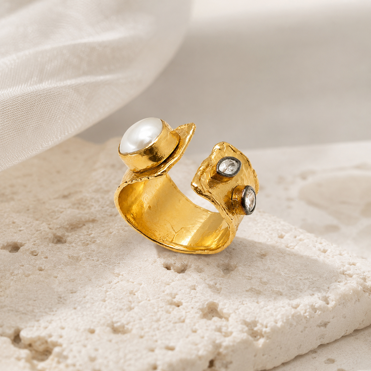 Gold-tone open cuff ring with a pearl-like center and polished finish.