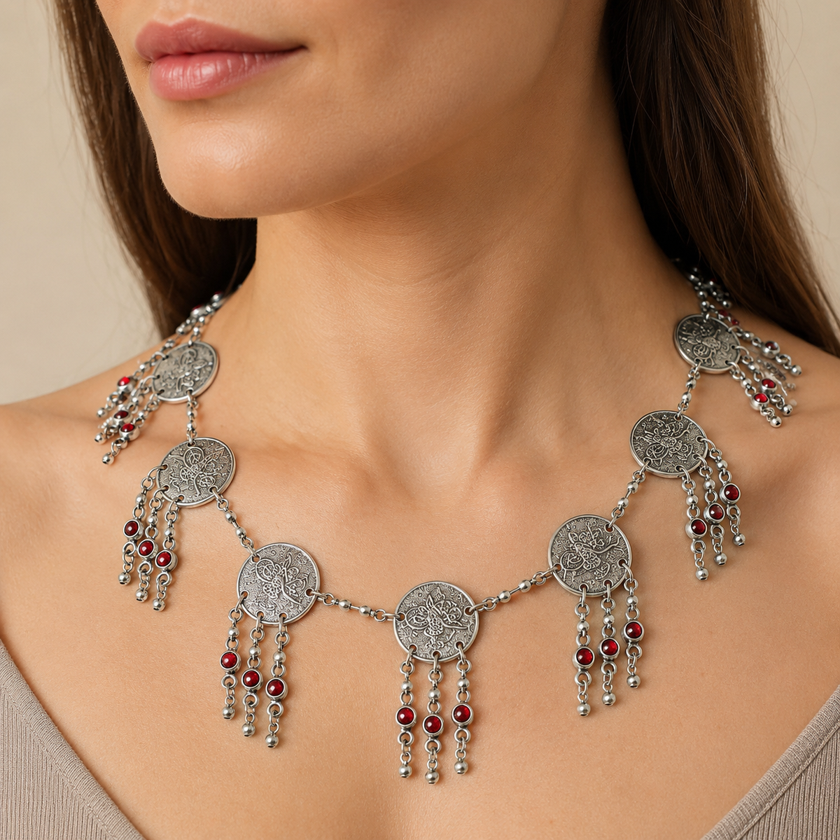 Silver-tone coin fringe necklace with red bead accents shown from above.
