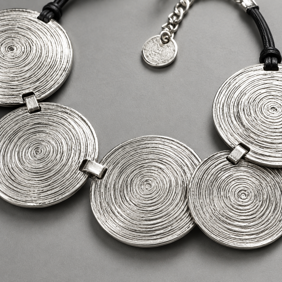 Close-up of the spiral disc pendant texture and silver-tone finish.