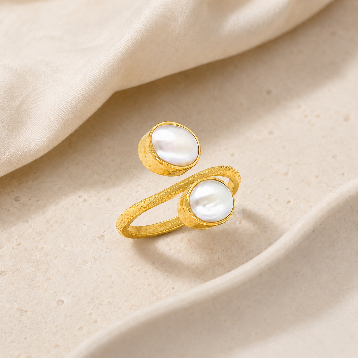 Close-up of a double stone gold-plated ring with pearl-like accents.