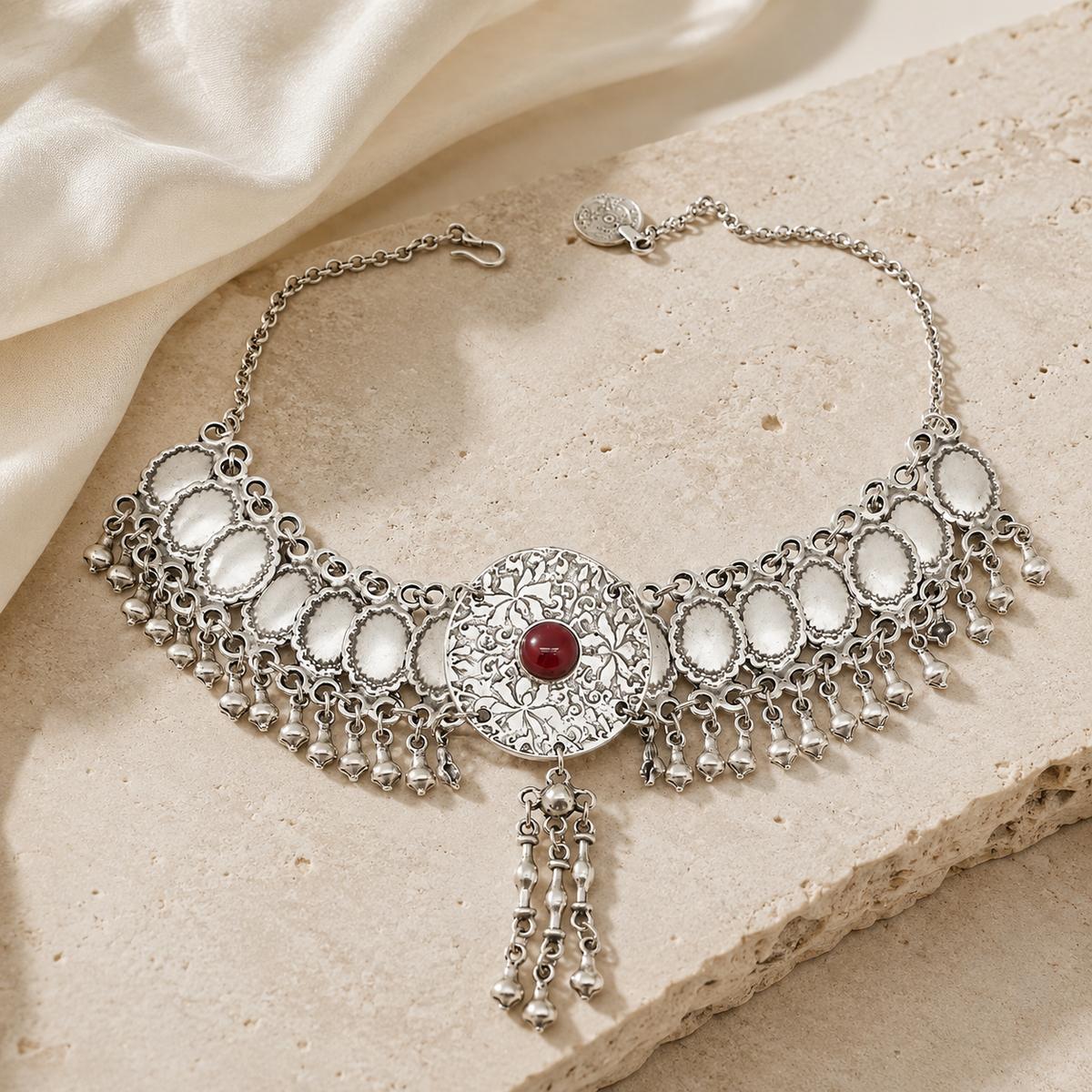 Silver-tone statement necklace with a red center stone and fringe detailing.