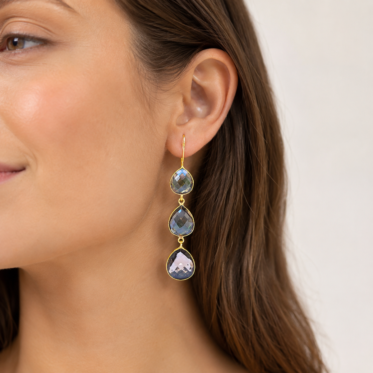 Front view of triple teardrop earrings with smoky faceted stones and gold-plated finish.