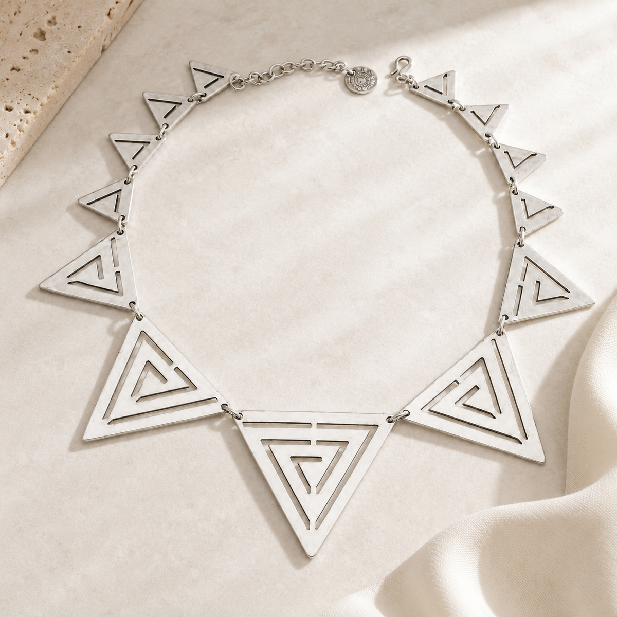 Geometric silver-tone necklace with linked triangle pendants.