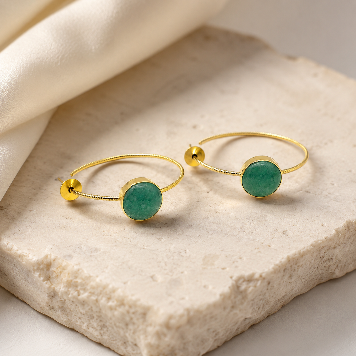 Pair of gold-plated hoop earrings with green aventurine discs on a clean background.