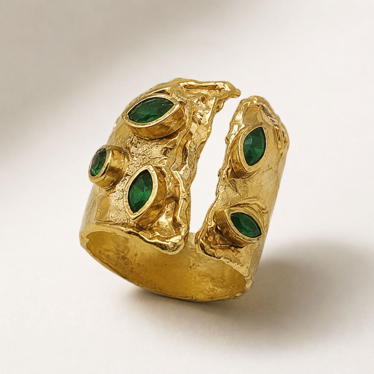 Side angle view of an open cuff ring with green stones