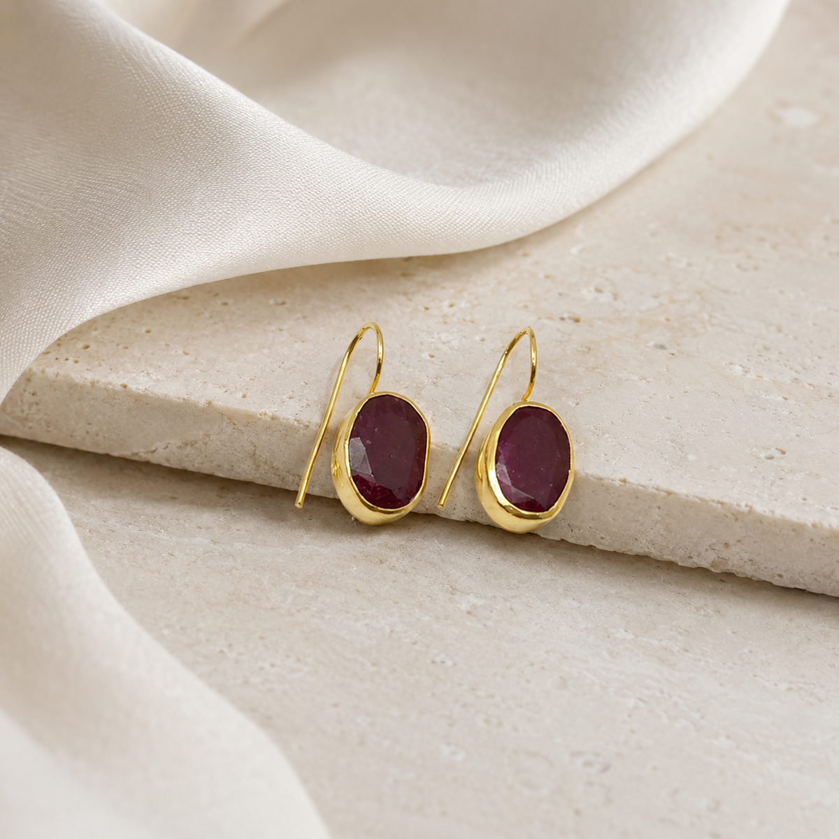 Gold-plated drop earrings with rich red stones and a polished finish.