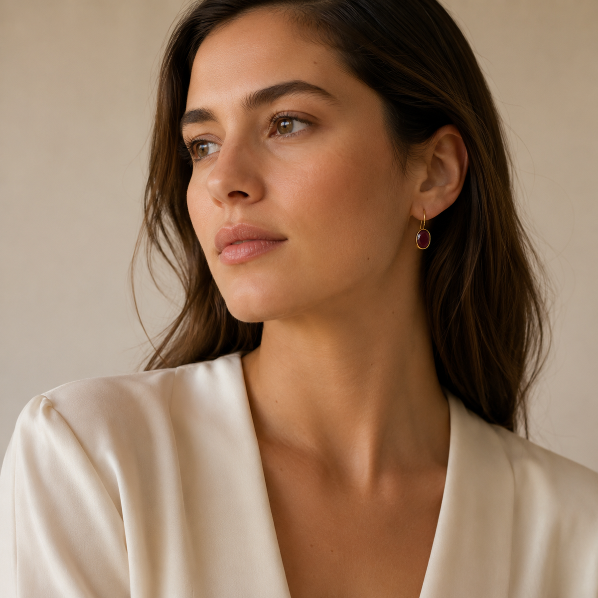 Gold-plated drop earrings with oval deep red stones in a clean studio view.