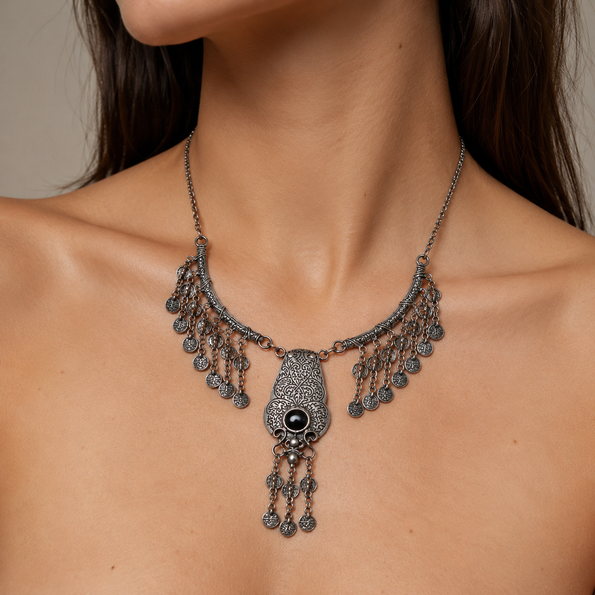 Silver-tone filigree necklace with a red stone center and dangling coin details.