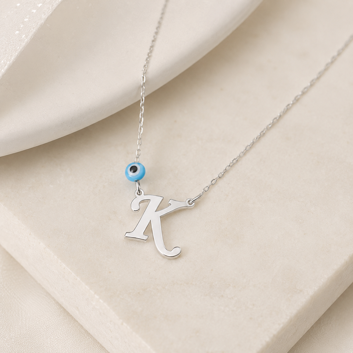 Angled view of a personalized initial necklace with a blue evil eye detail.